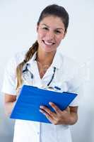 Portrait of female doctor writing on clipboard in hospital