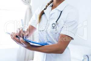 Female doctor writing on clipboard in hospital