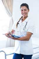 Portrait of female doctor writing on clipboard in hospital