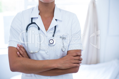 Mid-section of female doctor standing with arms crossed