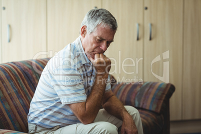 Upset senior man sitting in living room