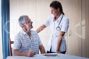 Doctor assisting a senior man while drawing in drawing book