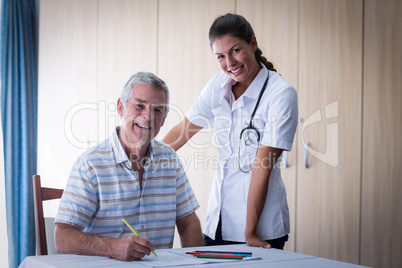 Portrait of doctor and senior man smiling while drawing in drawing book