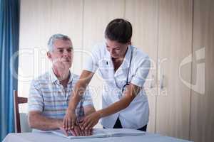 Female doctor helping patient in reading the braille book