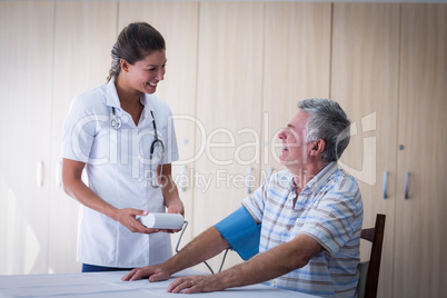 Female doctor checking blood pressure of senior man