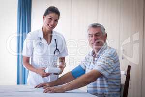 Portrait of female doctor checking blood pressure of senior man