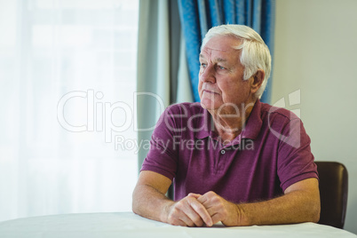 Thoughtful senior man sitting in living room