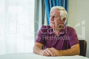 Thoughtful senior man sitting in living room