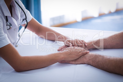 Mid section of female doctor consoling senior man in living room