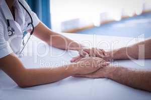 Mid section of female doctor consoling senior man in living room