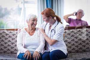 Senior woman and female doctor interacting in living room