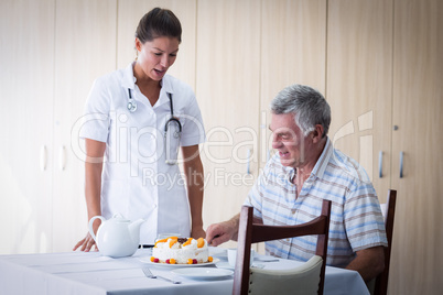 Female doctor celebration seniors man birthday in living room