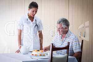 Female doctor celebration seniors man birthday in living room