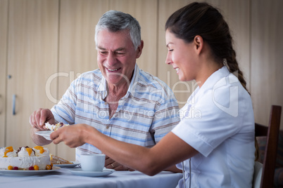 Senior man giving cake to doctor in living room
