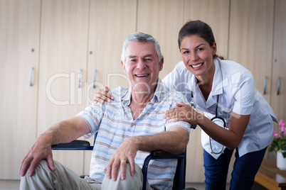 Portrait of smiling senior man and female doctor in living room