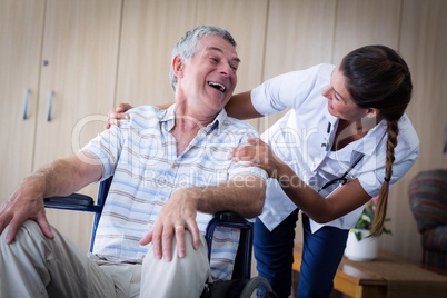 Happy senior man and doctor interacting in living room