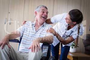 Happy senior man and doctor interacting in living room