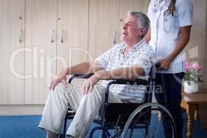 Female doctor carrying senior man on wheelchair