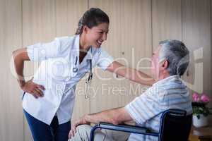 Happy senior man and doctor interacting in living room