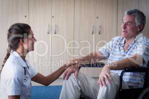 Female doctor consoling senior man in living room