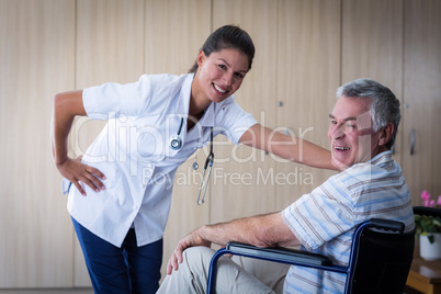 Portrait of smiling senior man and female doctor in living room