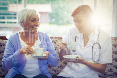 Smiling doctor and patient having tea
