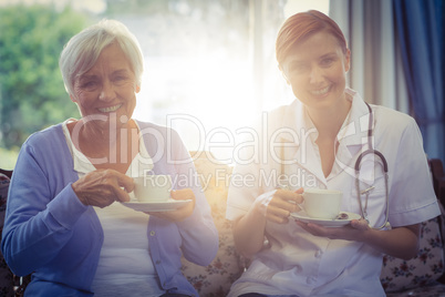 Portrait of smiling doctor and patient having tea