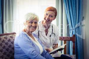 Smiling doctor helping senior woman to read a book