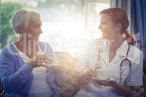 Smiling doctor and patient talking while having tea