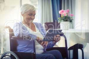 Happy senior woman on wheelchair using digital tablet