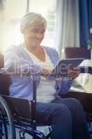 Happy senior woman on wheelchair using digital tablet