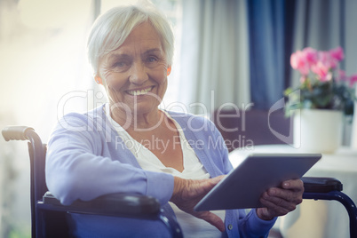 Happy senior woman on wheelchair using digital tablet