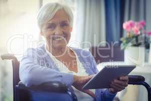 Happy senior woman on wheelchair using digital tablet