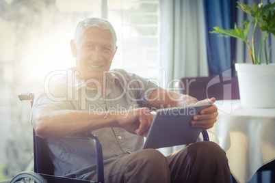 Happy senior man on wheelchair using digital tablet