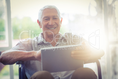 Senior man on wheelchair using digital tablet