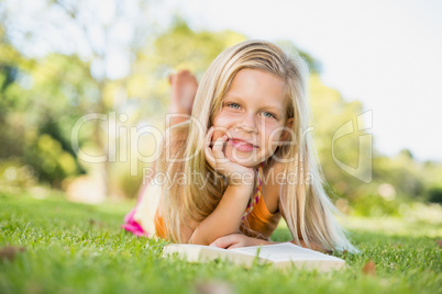 Young girl lying on grass with book