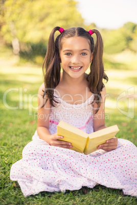 Young girl reading book in park