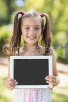 Young girl holding digital tablet in park