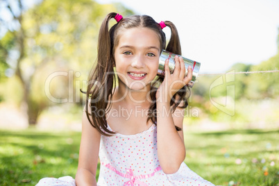 Young girl listening through tin can phone