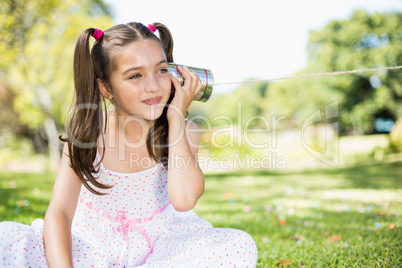 Young girl listening through tin can phone