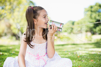 Young girl speaking through tin can phone