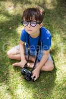 Young boy sitting on grass with a camera
