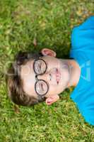 Young boy in spectacle lying on grass
