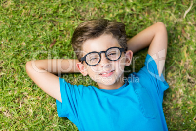 Young boy in spectacle lying on grass