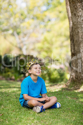 Young boy wearing a crown and sitting on grass