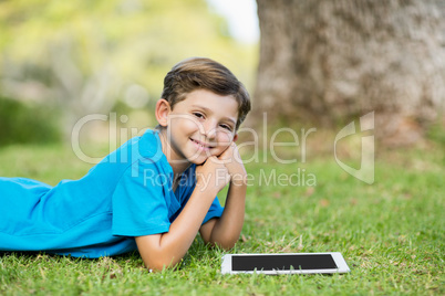 Young boy lying on grass with digital tablet