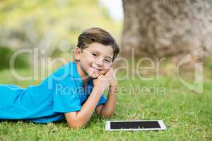 Young boy lying on grass with digital tablet
