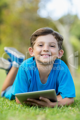 Young boy lying on grass with digital tablet