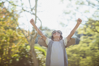 Excited boy standing in park with arms raised