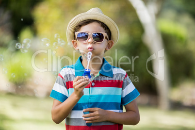 Young boy in sunglasses blowing bubbles through bubble wand